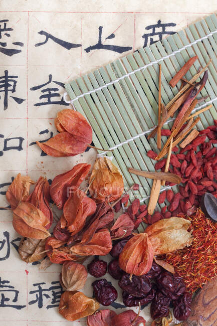 Китайские травы на бамбуковом коврике и бумаге с иероглифами — стоковое фото