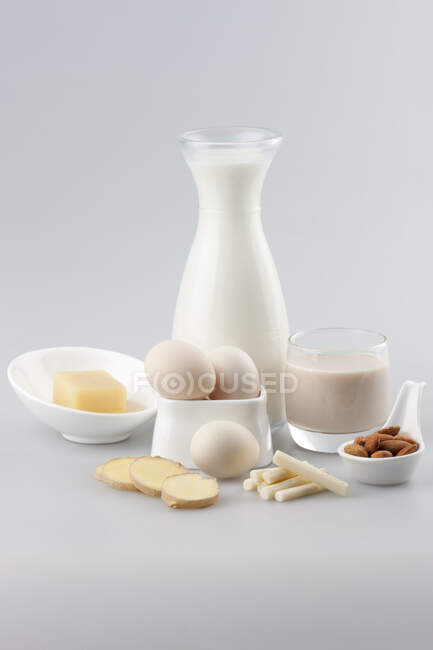 Lait de soja et d'amande en récipients en verre contenant des œufs, des noix et du gingembre haché — Photo de stock