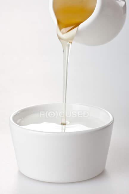Derramando mel em tigela com iogurte, close-up tiro — Fotografia de Stock