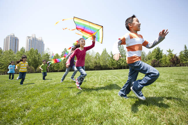 Chinese children playing with kite in field — Stock Photo