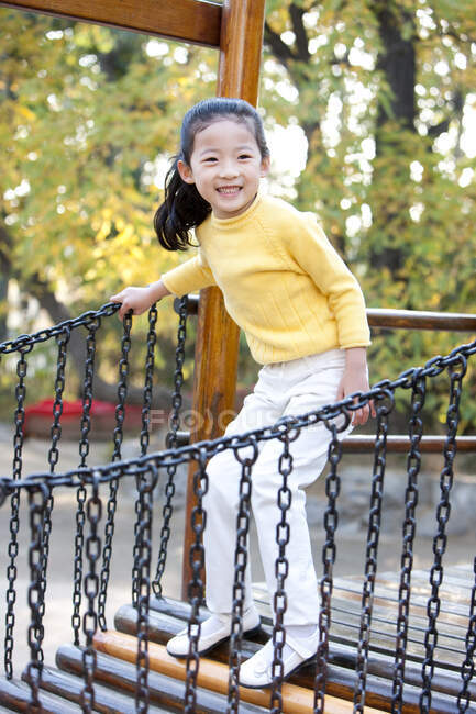 Chinesisches Mädchen spielt auf Spielplatz-Spielzeugbrücke — Stockfoto