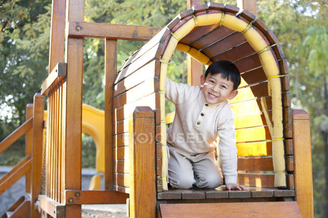 Rapaz chinês a rastejar através do túnel no parque infantil — Fotografia de Stock