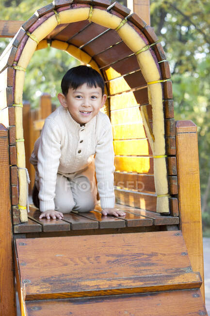 Chinese boy crawling through tunnel in playground — Stock Photo