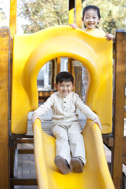 Chinese children playing on playground slide — Stock Photo