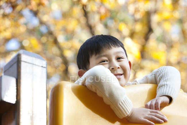 Chinese boy playing on playground slide — Stock Photo