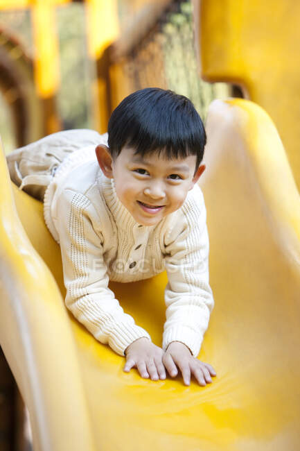 Menino chinês brincando no playground slide — Fotografia de Stock