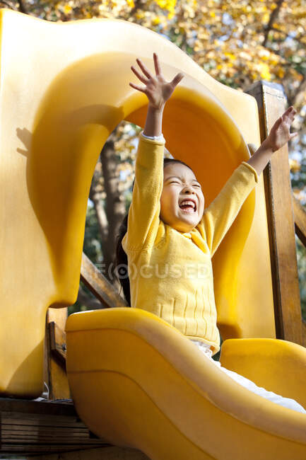 Esctatic chica china jugando en el patio de diapositivas - foto de stock