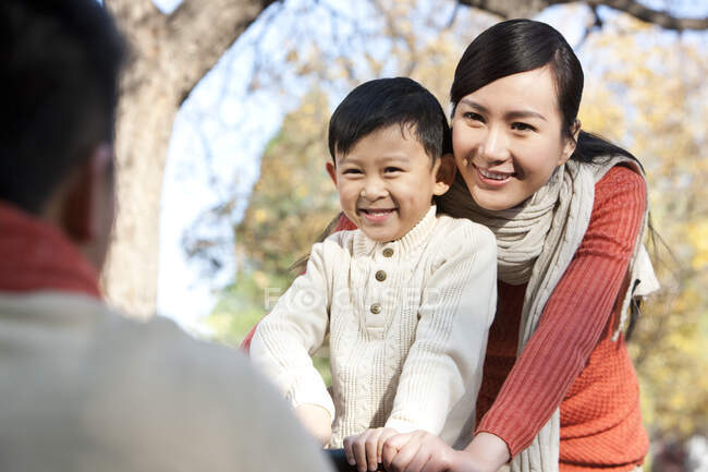 Glückliche chinesische Familie spielt Wippe im Park — Stockfoto