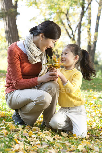 Китайська мати й дочка збирають листя. — стокове фото
