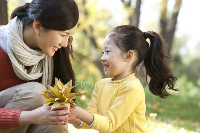 Mère et fille chinoises ramassant des feuilles — Photo de stock