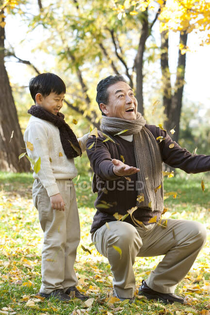 Garçon chinois avec grand-père regarder les feuilles tomber — Photo de stock