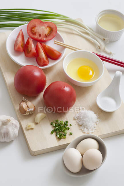 Various ingredients on wooden board, tomatoes, eggs and herbs — Stock Photo