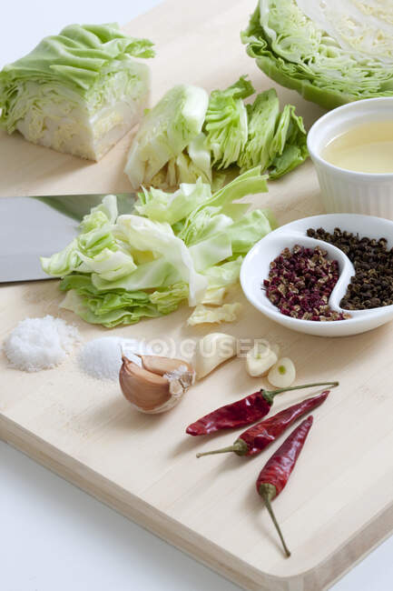 Chopped cabbage with garlic and dried chili peppers on cutting board — Stock Photo