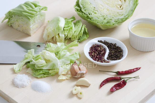 Chopped cabbage, garlic, dried chili peppers, spices and salt on cutting board — Stock Photo