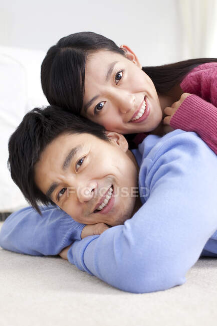 Joven pareja china tumbada en el suelo de cerca - foto de stock