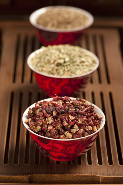 Different spices in traditional chinese bowls on wooden surface — Stock Photo