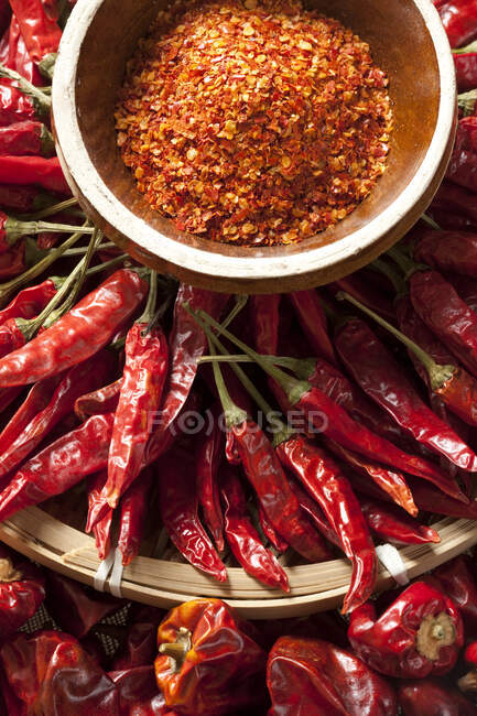 Dried chili peppers and seeds in bowl, top view — Stock Photo