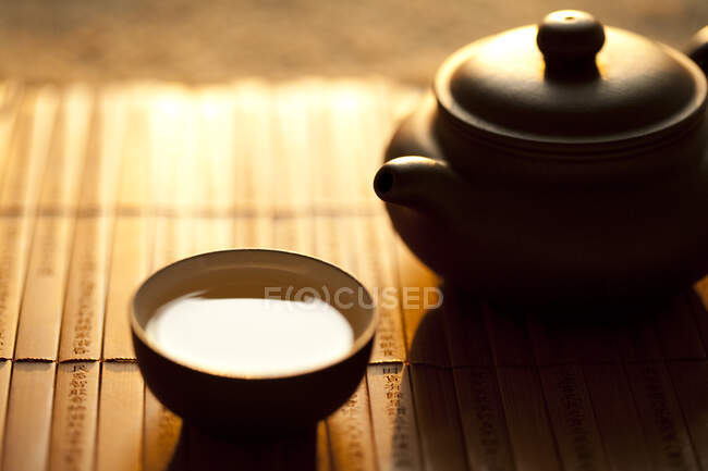 Tazza di tè e pentola sul tappetino di bambù, colpo da vicino — Foto stock