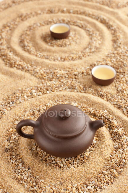 Blick auf Teekanne und Tassen auf Sandoberfläche — Stockfoto