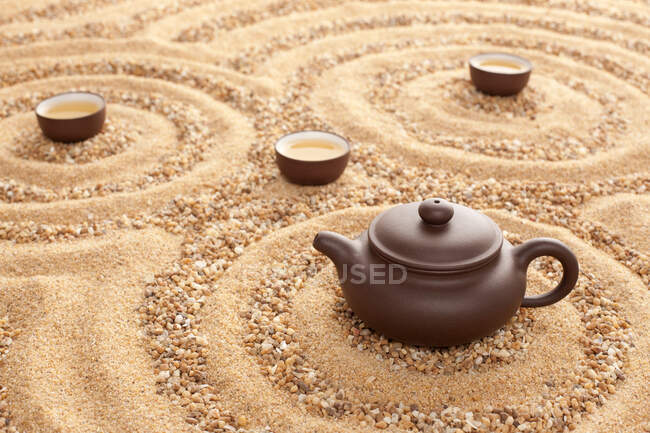 Tee in Kannen und Tassen auf Sandoberfläche — Stockfoto