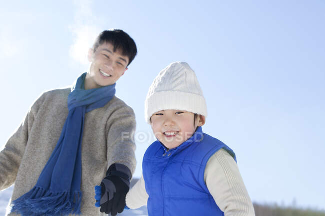 Chinese father playing with son in snow — Stock Photo