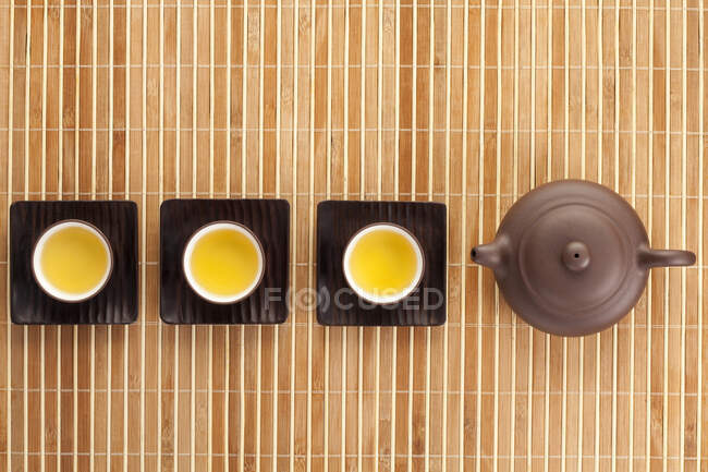 Tea set on bamboo mat, top view of pot and cups — Stock Photo