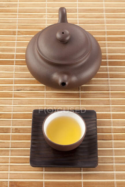 Tasse de thé et pot sur tapis de bambou, plan rapproché — Photo de stock