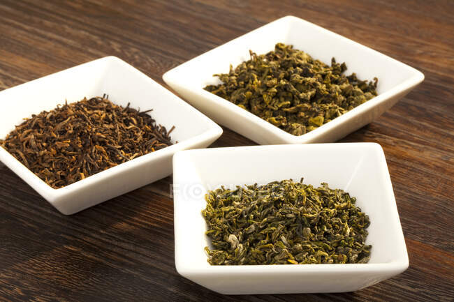 Divers thé chinois sec dans des bols sur une table en bois — Photo de stock