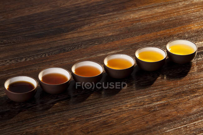 Tassen mit verschiedenen Sättigungstees auf Holzoberfläche — Stockfoto