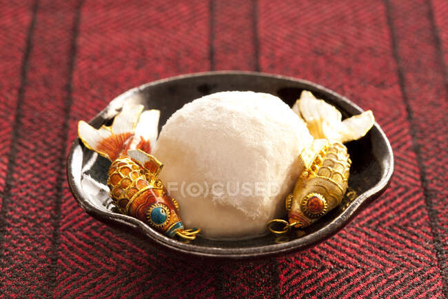 Steamed rice cake with sweet stuffing served with two decorative fish — Stock Photo