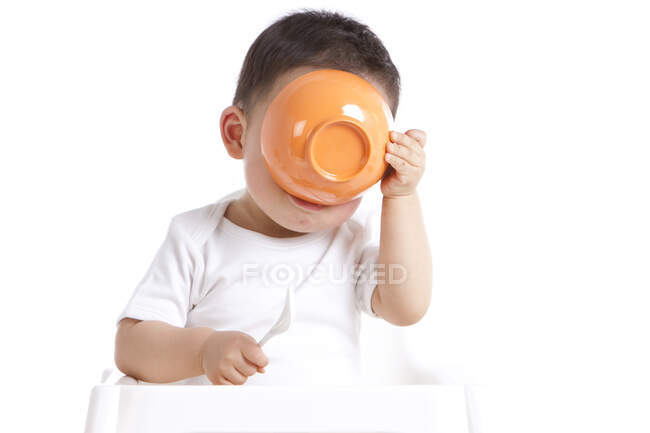Niño chino con cuchara y tazón - foto de stock