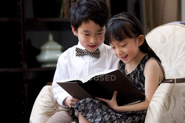 Little Chinese boy and girl reading book in study — Stock Photo