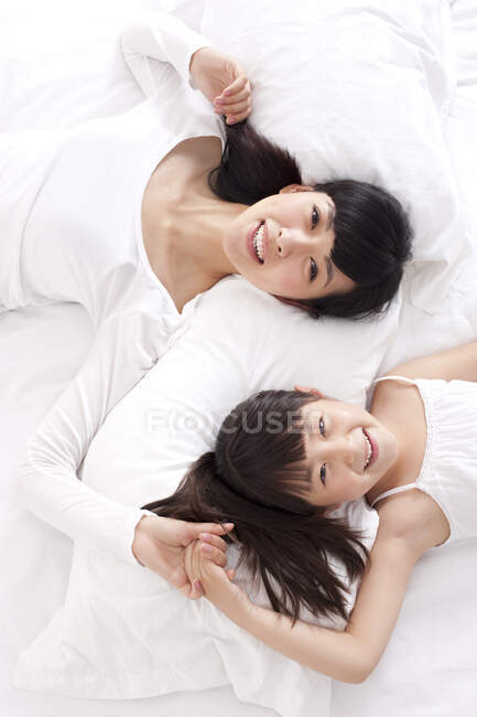 Chinese mother and daughter lying in bed — Stock Photo