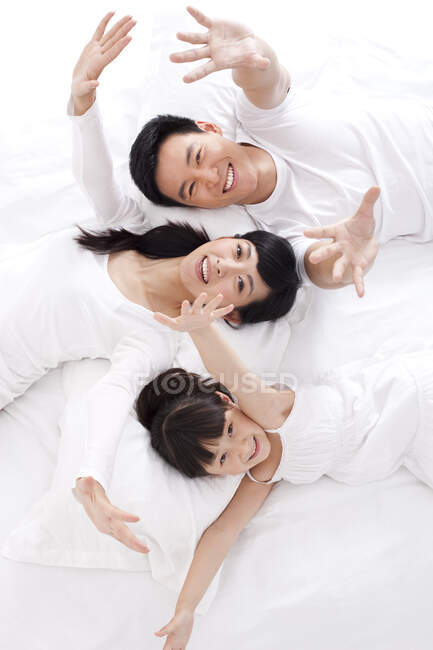 Счастливая китайская семья лежит в постели — стоковое фото