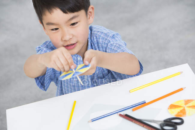 Chinese boy making a paper toy — Stock Photo