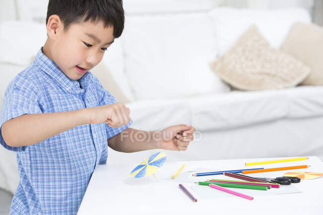 Китайський хлопчик виготовляє паперові іграшки. — стокове фото