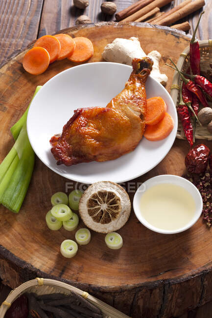 Poulet braisé dans une assiette entourée d'ingrédients — Photo de stock