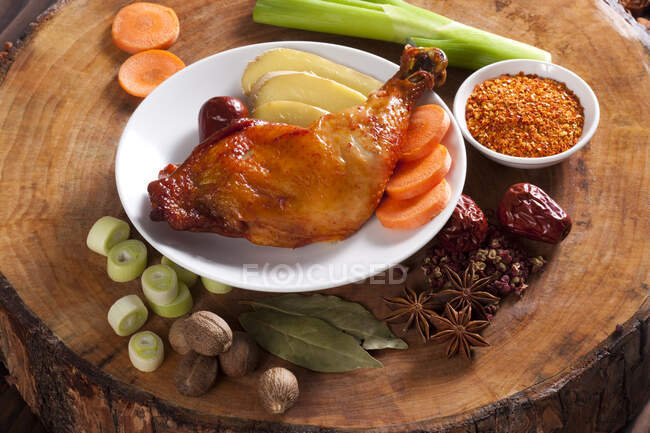 Pollo estofado en el plato rodeado de ingredientes - foto de stock