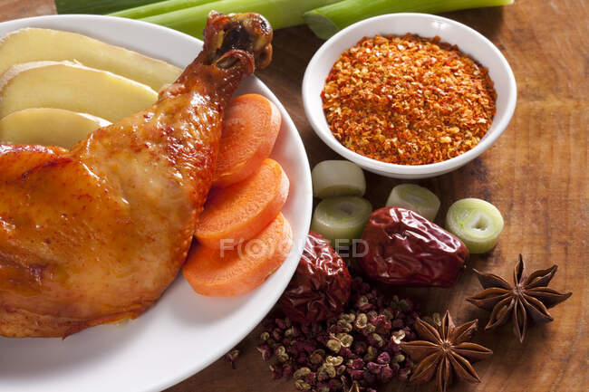 Braised chicken with ginger and carrot on plate, spices on table — Stock Photo