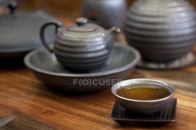 Tetera china y taza de té en mesa de madera - foto de stock