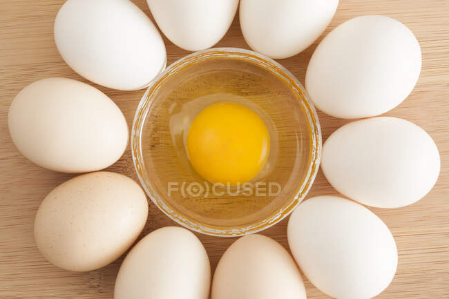 Eggs in circle surrounding glass bowl with liquid egg — Stock Photo