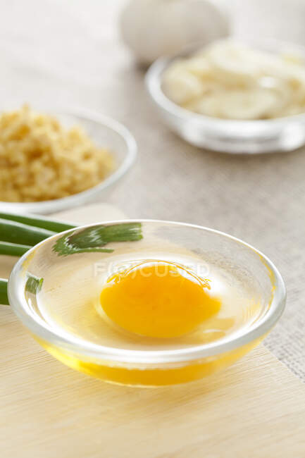 Egg in glass bowl with ginger, onion and garlic — Stock Photo