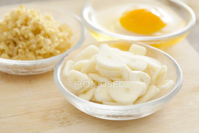 Egg, chopped ginger and garlic slices in glass bowls — Stock Photo