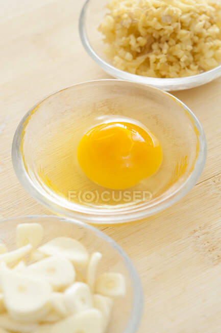 Egg, chopped ginger and garlic slices in glass bowls — Stock Photo