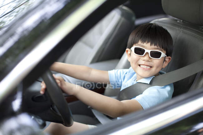 Chico chino emocionado fingiendo conducir coche - foto de stock