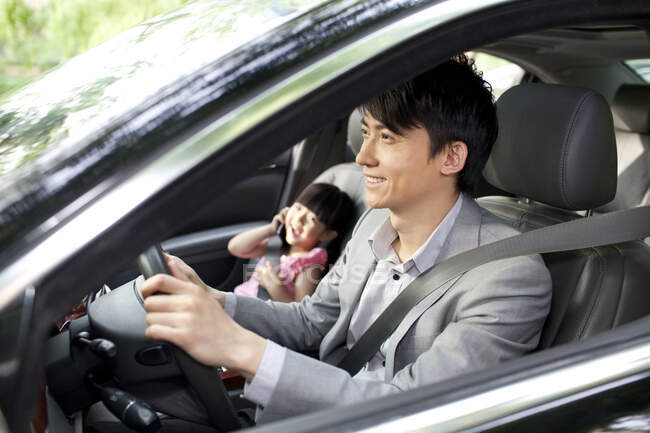 Веселий китайський батько їде з дочкою на передньому сидінні. — стокове фото