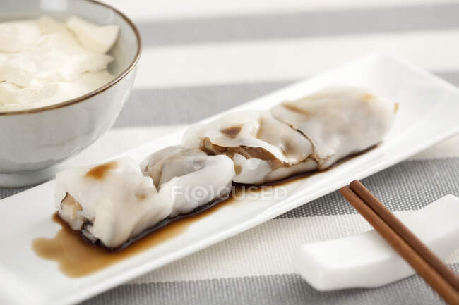 Rice rolls served on plate and chopsticks on stand — Stock Photo