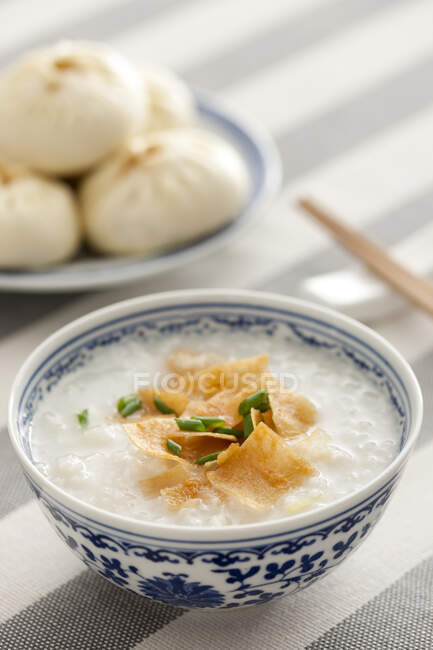 Китайская еда, рисовая каша в миске с чипсами и зеленым луком — стоковое фото