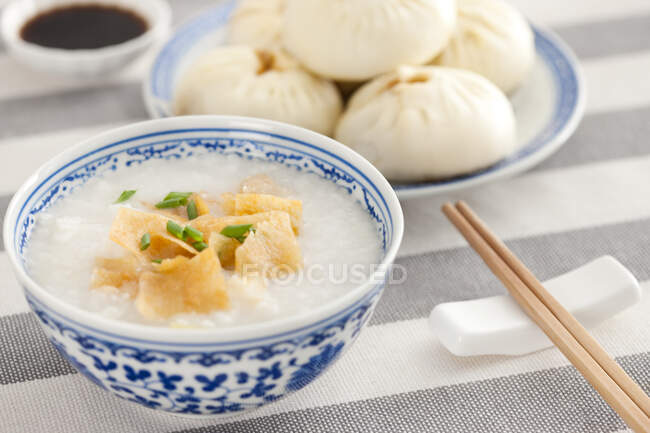 Ciotola di riso porridge e panini al vapore serviti sul tavolo — Foto stock