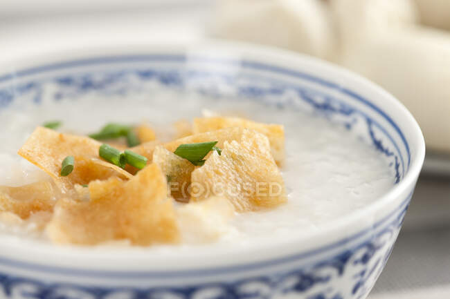 Comida china, gachas de arroz en tazón con papas fritas y cebolla verde - foto de stock